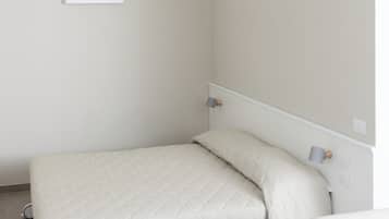 Une chambre à coucher au style minimaliste, avec un lit, une table de chevet et une petite table.