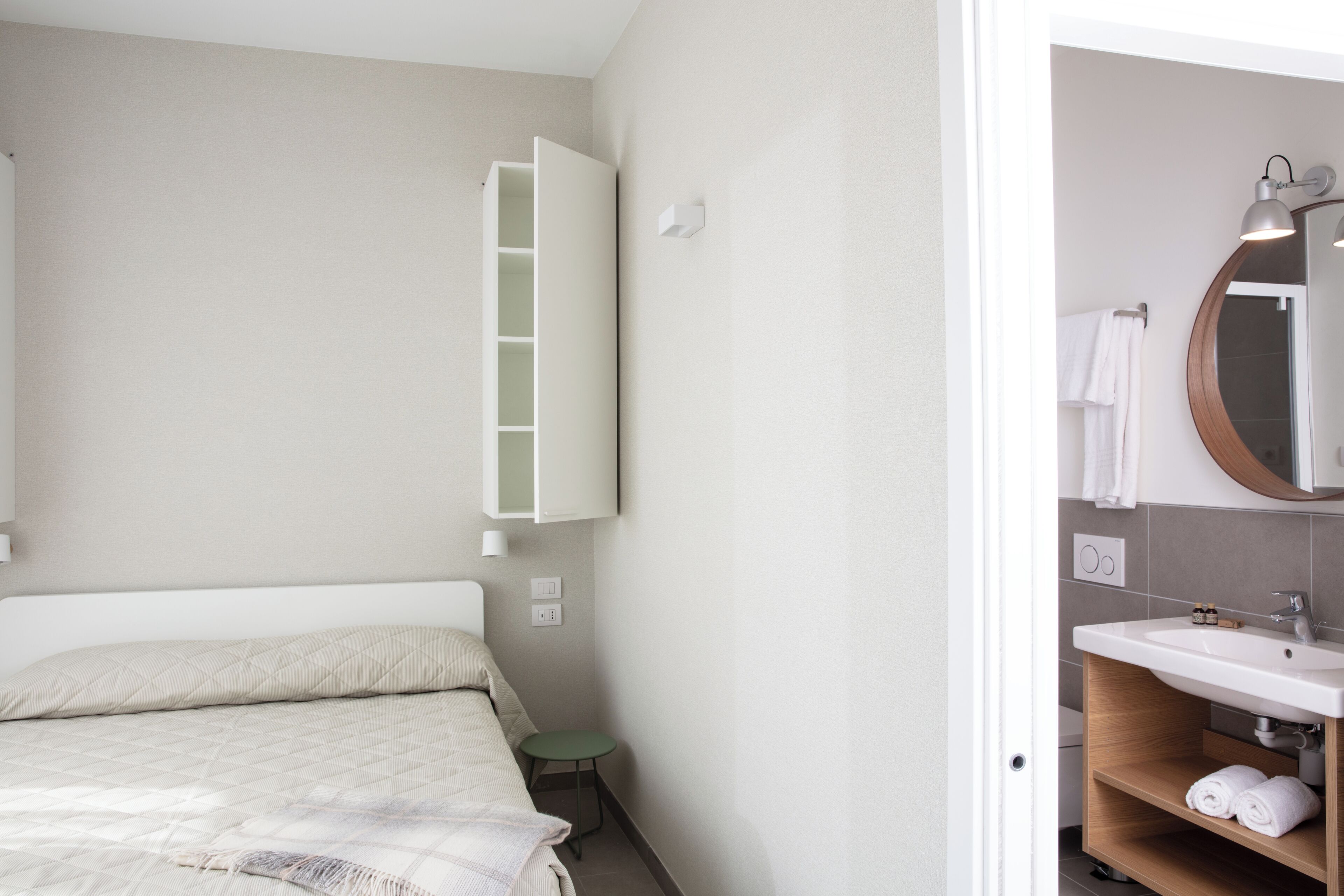 Una camera da letto con un letto, un comodino e un mobiletto a parete.