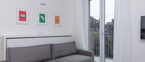 A modern living room with a grey sofa, a flat-screen TV, and a sliding glass door to a balcony.