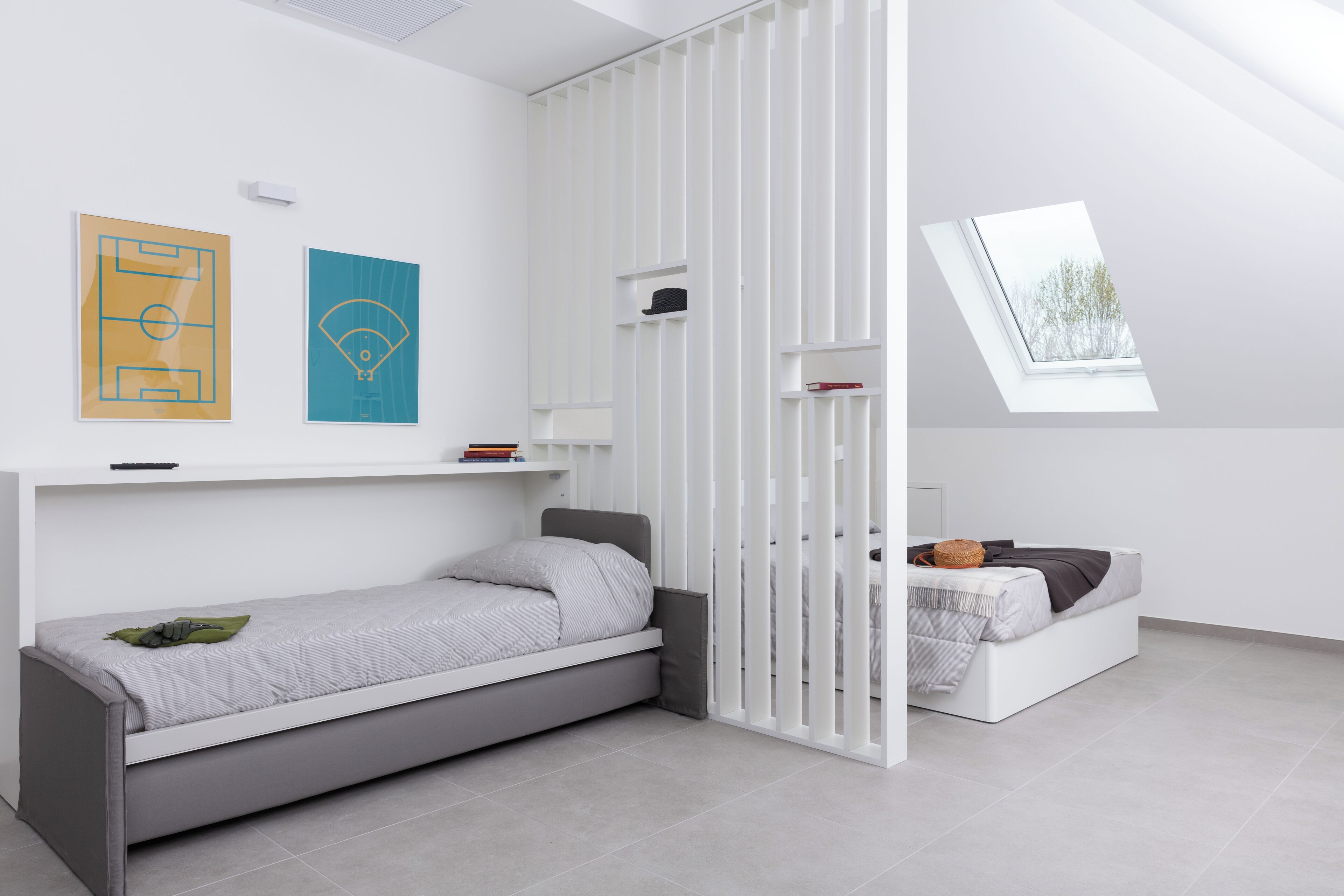 Ein modernes, minimalistisches Schlafzimmer mit einem Einzelbett, einem Schlafplatz in der Schlaffküche und einem Oberlicht.