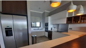 Una cocina moderna con electrodomésticos de acero inoxidable, encimera de madera e iluminación colgante.
