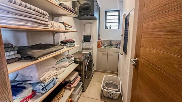 Une buanderie avec des étagères remplies de vêtements pliés, un lave-linge, un sèche-linge et une petite fenêtre.