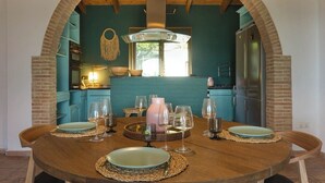 Un comedor con una mesa de madera dispuesta para cuatro personas, rodeada de sillas color turquesa.