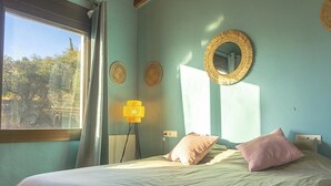 Un dormitorio con cama, ventana y lámpara de pared.
