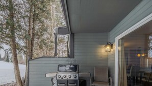 Une terrasse extérieure couverte, équipée d’un barbecue, d’une chaise et d’une table.