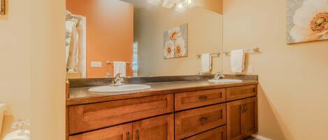 A bathroom with wooden cabinets, a double sink, and a large mirror.