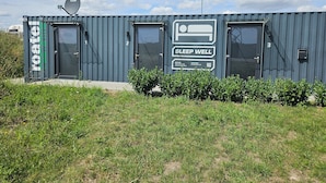 A modern, modular building with numbered doors, a satellite dish, and a prominent 'SLEEP WELL' sign. - Roatel Schkeuditz A9 (Schkeuditz)