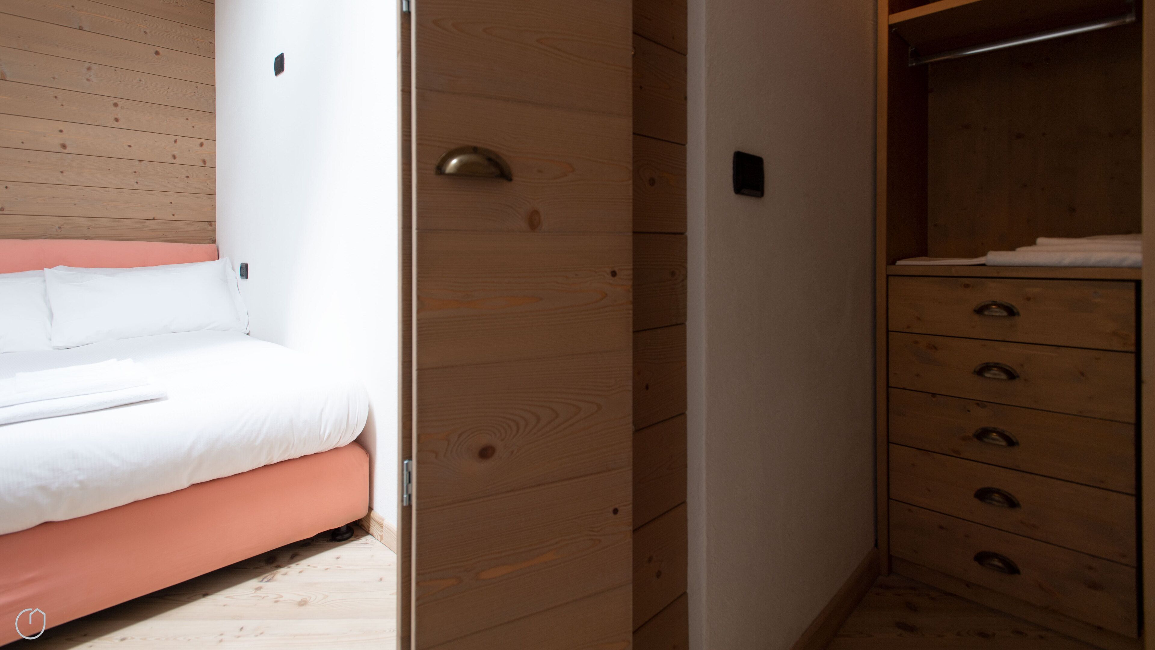 A bedroom with a bed, a wooden wardrobe, and a dresser.