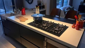 Moderni keittiö, jossa on kaasuliesi, leikkuulauta ja kattila työtasolla.