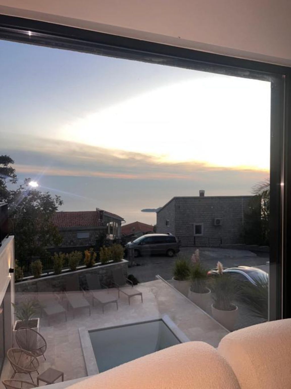 A balcony with a view of a residential area, a car, and a swimming pool.