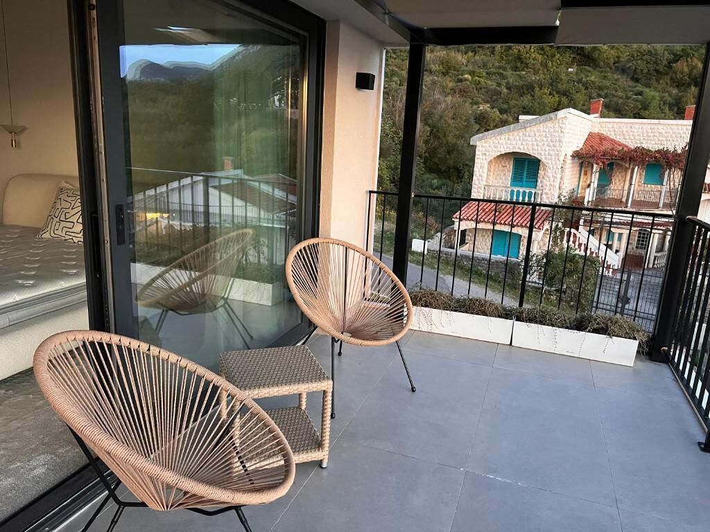 Un balcon avec des fauteuils en osier et une porte vitrée donnant sur une pièce.