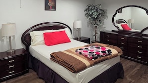 Une chambre à coucher avec un lit, des tables de chevet, un miroir, une plante en pot et un luminaire au plafond.