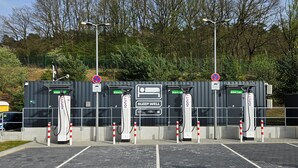Un espace de stationnement équipé de plusieurs bornes de recharge pour véhicules électriques, chacune étant signalée par une pancarte indiquant « Reposez-vous bien », et une pancarte « Stationnement interdit » au-dessus de l’entrée.
