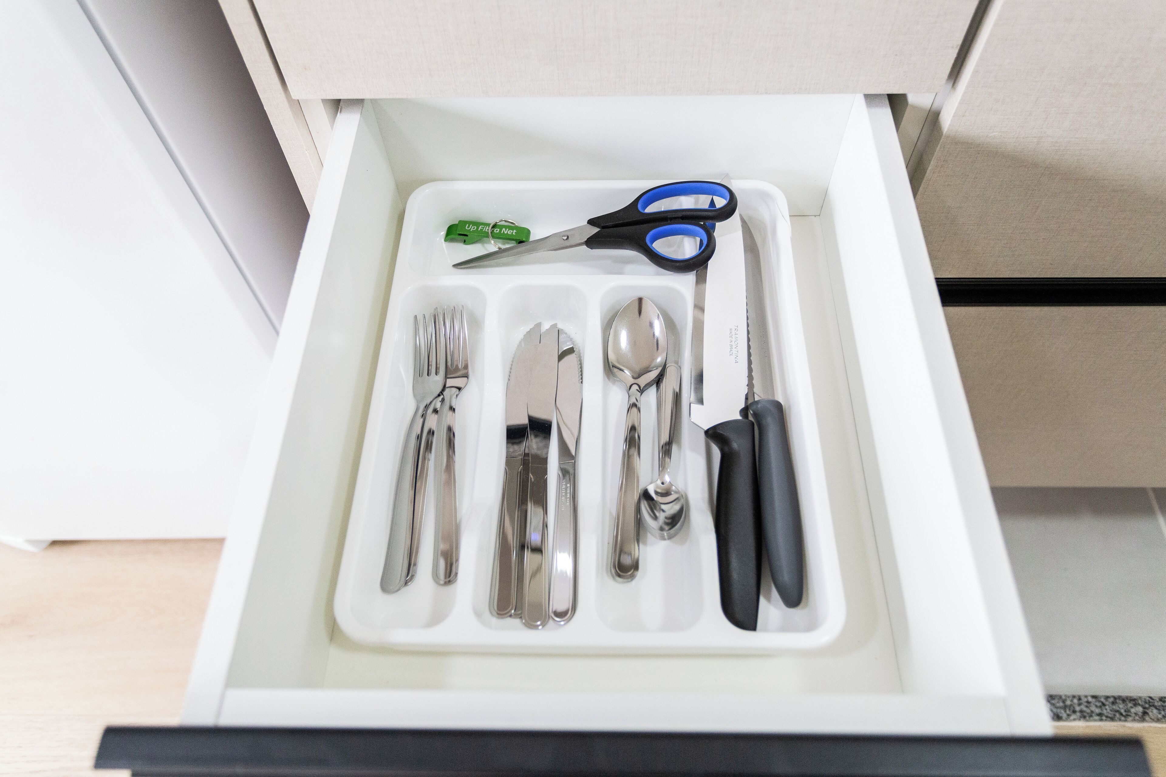 A drawer containing a set of silverware, a spoon, a knife, and a pair of scissors.