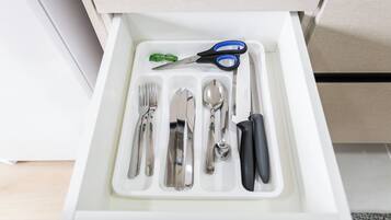 A drawer containing a set of silverware, a spoon, a knife, and a pair of scissors.