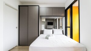 Una habitación de hotel moderna con una cama, un televisor y un armario con puerta corrediza.