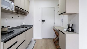 Una cocina compacta con microondas, fregadero y cafetera.