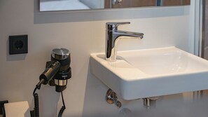 A bathroom with a white sink, chrome faucet, and a hairdryer plugged in. - Roatel Busdorf A7 (Busdorf)
