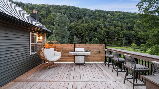 A deck with a grill, chairs, and a table.