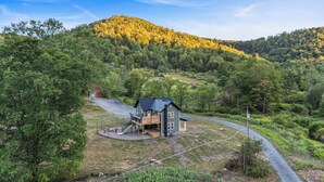 A house with a deck, surrounded by a forested hillside.