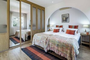 Ein Hotelzimmer mit einem großen Bett, einem Spiegel, einem Kleiderschrank und Blick ins Freie.