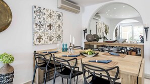 Un comedor con una mesa de madera dispuesta para cuatro, sillas negras y un adorno en la pared.
