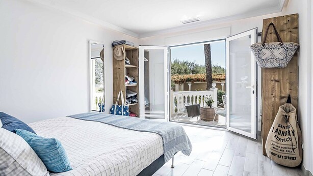 Un dormitorio con cama, armario y un ventanal grande.
