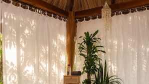 Una habitación con techo de paja, una esterilla de yoga, una cesta de mimbre y equipo de ejercicio.