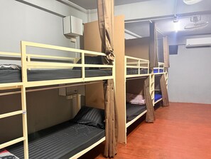Ein Schlafsaalzimmer mit Stockbetten, einem Deckenventilator und einer Klimaanlage.