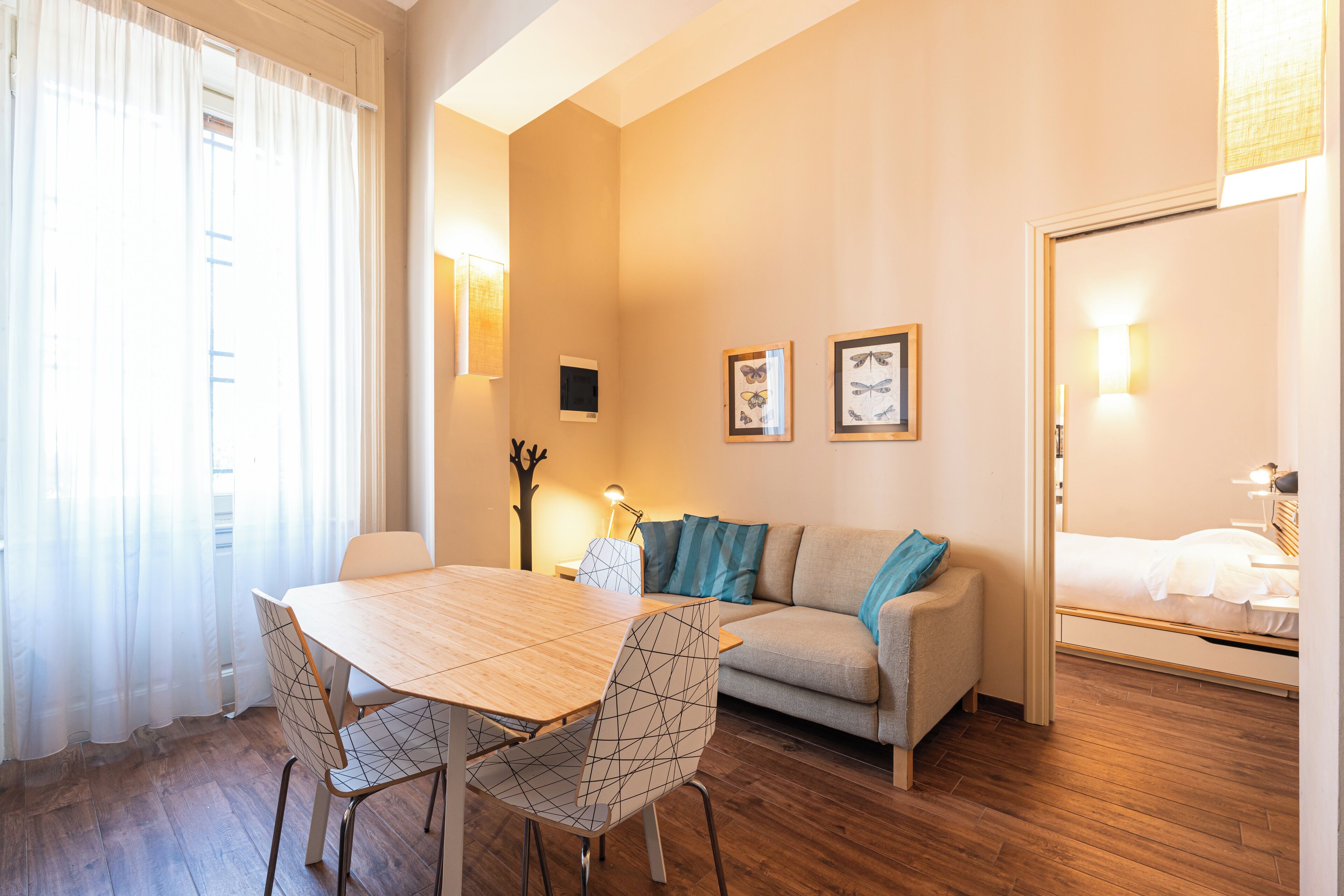 Una sala acogedora con una mesa de madera, dos sillas, un sofá y una cama.