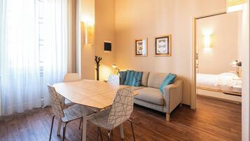 Una sala acogedora con una mesa de madera, dos sillas, un sofá y una cama.
