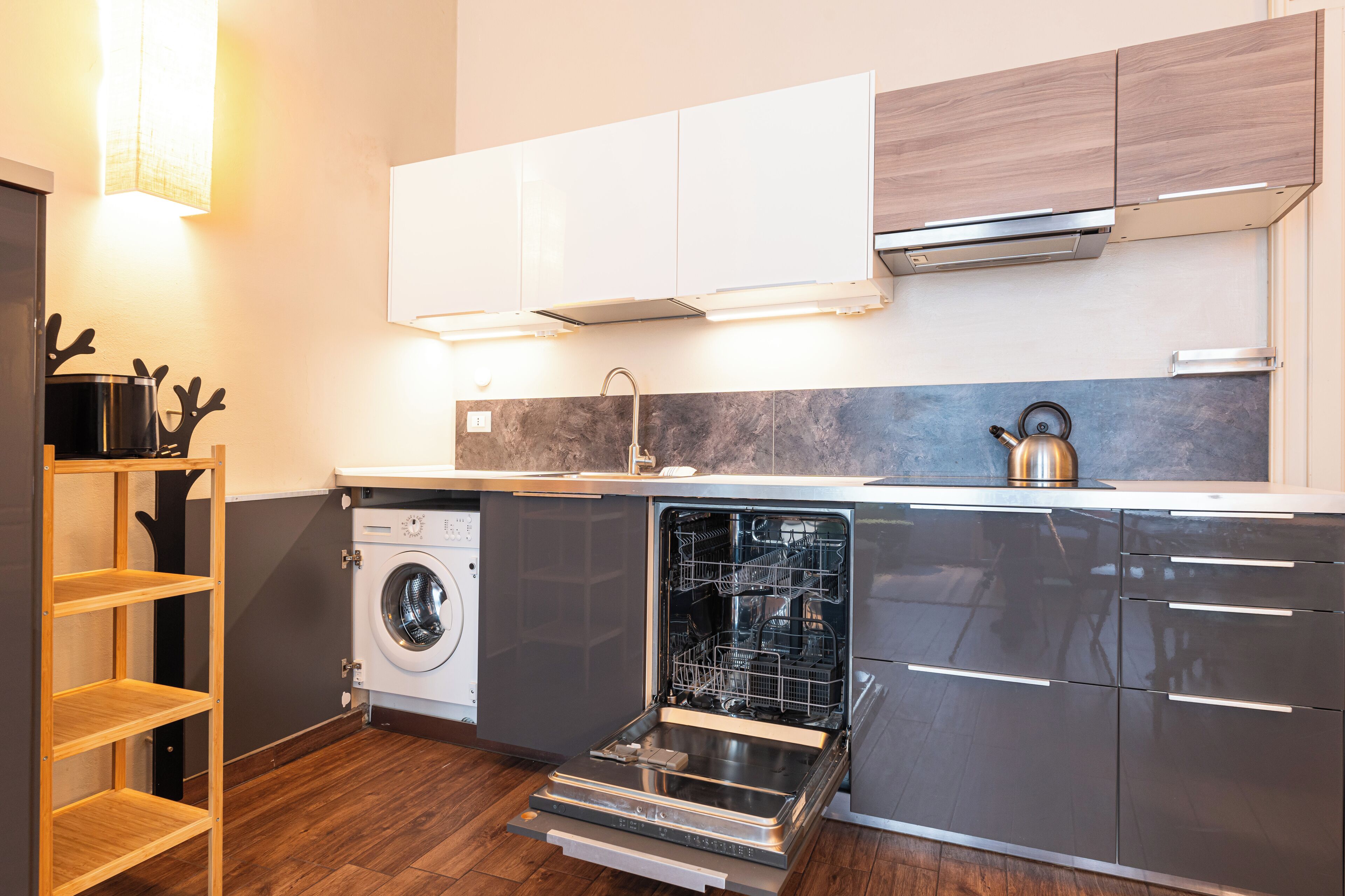 Una cocina moderna con lavavajillas integrado, lavadora y estantes de madera.