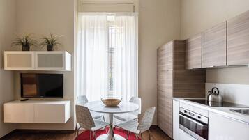 A modern kitchen with white cabinets, a built-in oven, and a kettle on the countertop.