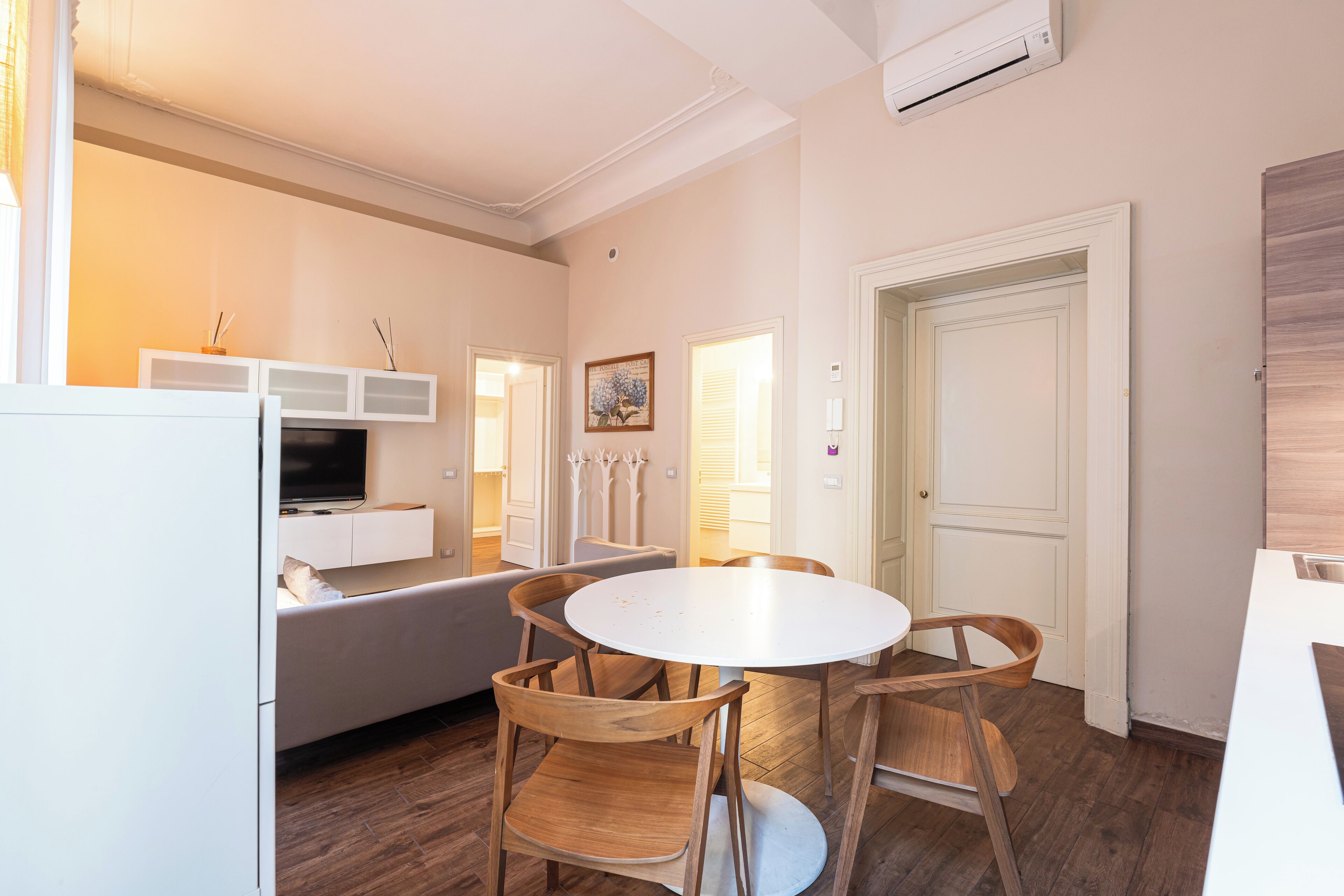 A modern kitchen with a round table, wooden chairs, and built-in white cabinets.