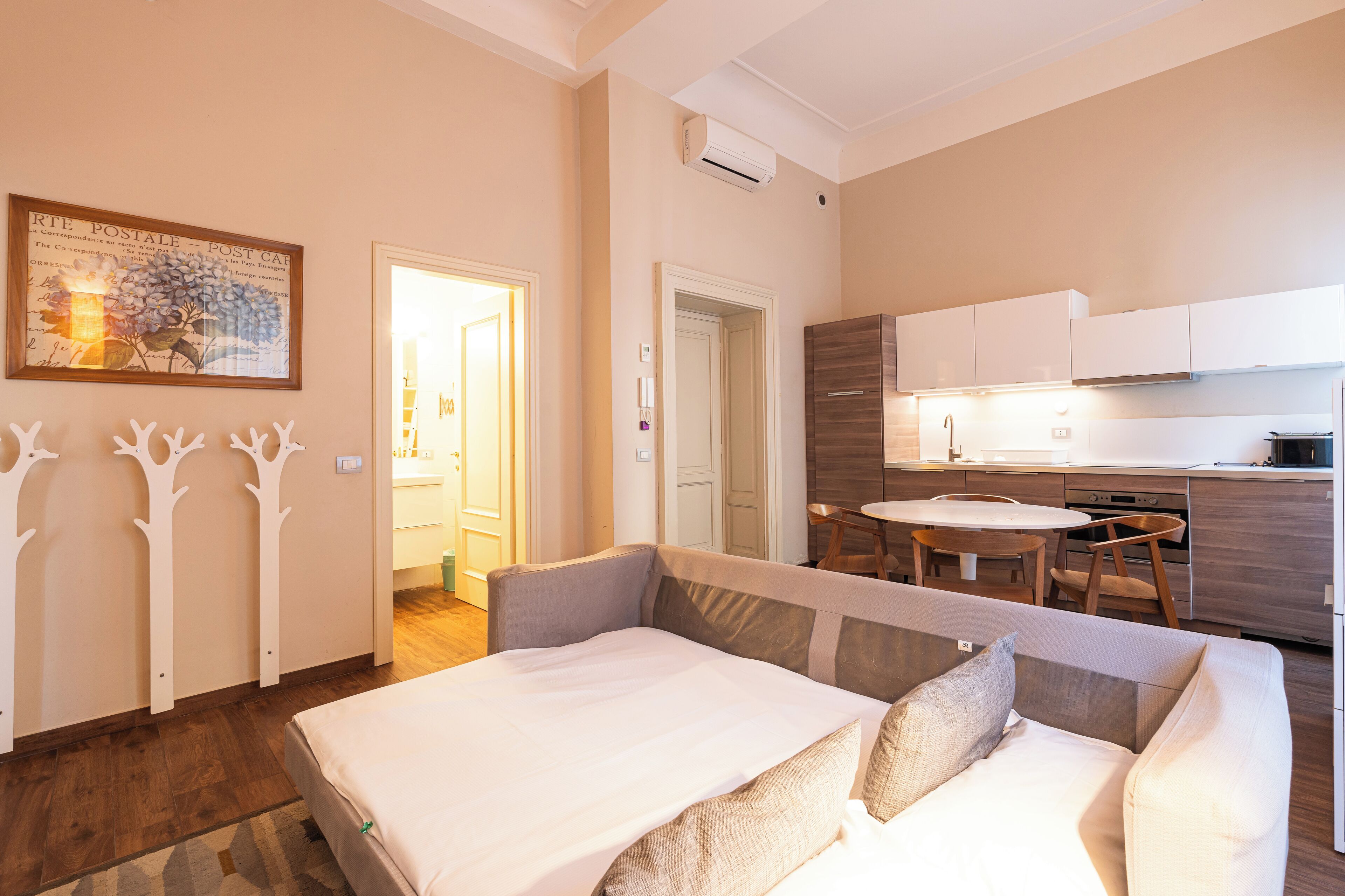 A modern bedroom with a bed, a dining table, and a kitchen area.