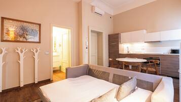 A modern bedroom with a bed, a dining table, and a kitchen area.