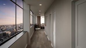 A corridor with large windows, a view of a cityscape, a dining area with a table and chairs, and a potted plant. - Vintedge Residences (Lyndhurst)