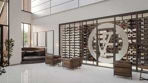 Moderni sisustus, jossa on viinikellari, nahkasohvat ja suuri lasiseinä, jonka muotoilu on pyöreä.