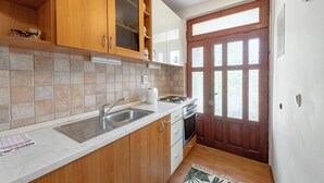 A kitchen with wooden cabinets, a double sink, and a stove. - Madonna Field Apartment II - Peaceful 1BR for 3 in Lapad (Dubrovnik)