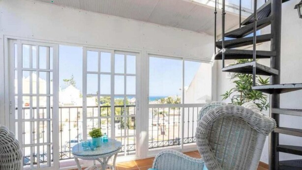 A balcony with wicker furniture, a glass table, and a view of the sea. - 1040  Casa Brisa Azul (Nerja)