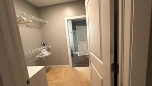 A hallway with a closet, a hanging rack, and a door leading to another room.