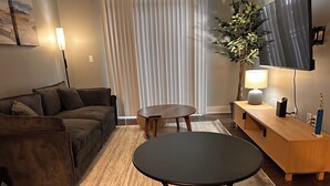 A modern living room with a sofa, a round table, a TV, and a plant.
