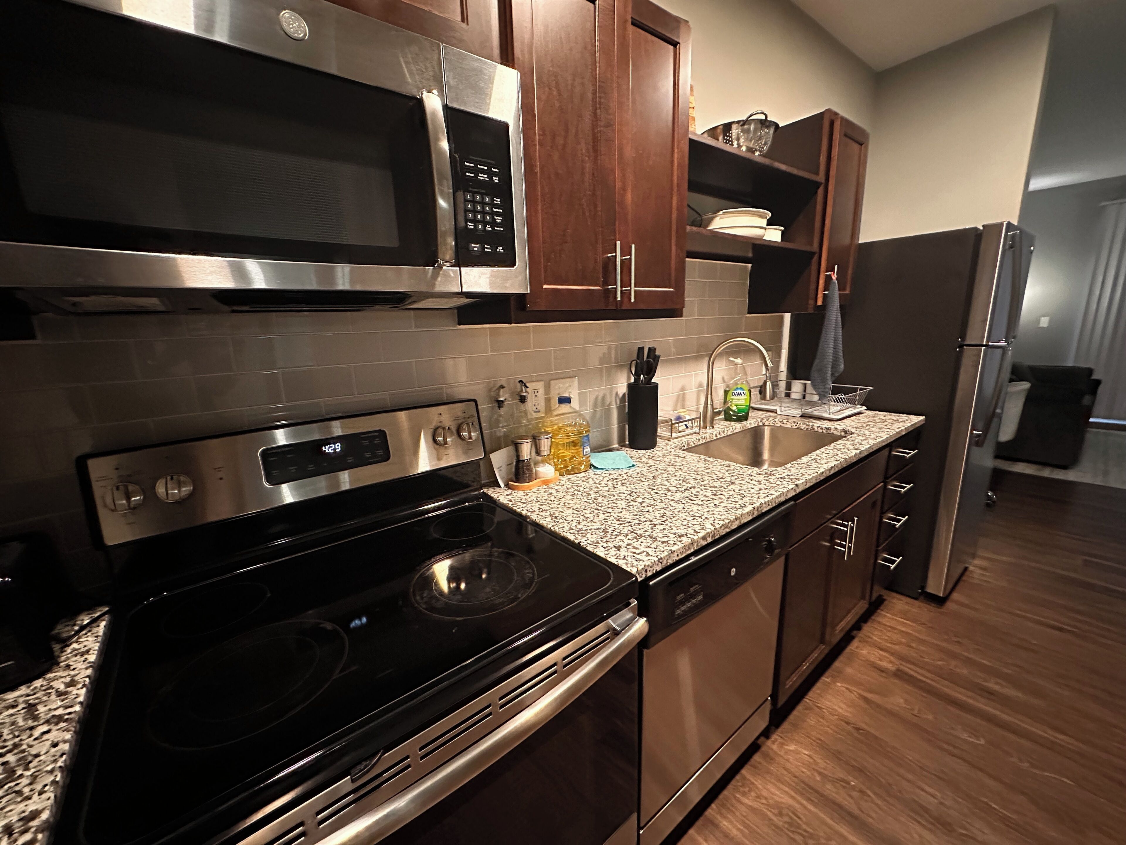 A modern kitchen with stainless steel appliances, granite countertops, and wooden cabinets.
