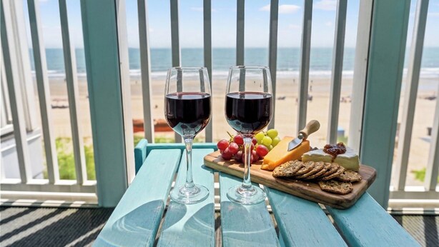 To glas rødvin på et bord med udsigt til stranden.