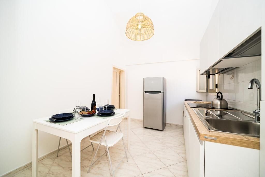 A compact kitchen with a white table set for dining, a stainless steel refrigerator, and a modern sink.