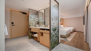 A modern hotel room with a wooden door, a vanity with a mirror, a bed, and a large window. - Hilton Garden Inn Shenzhen Luohu Port (Shenzhen)