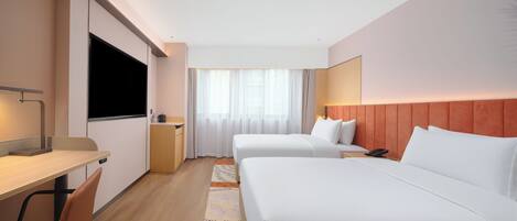 Habitación de hotel con dos camas, un escritorio, un televisor y una ventana con cortinas.