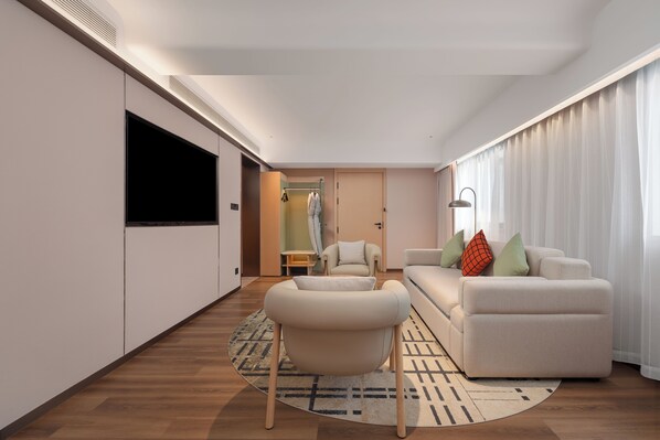 Una sala de estar moderna con un sofá, un sillón y un televisor de pantalla plana montado en la pared.