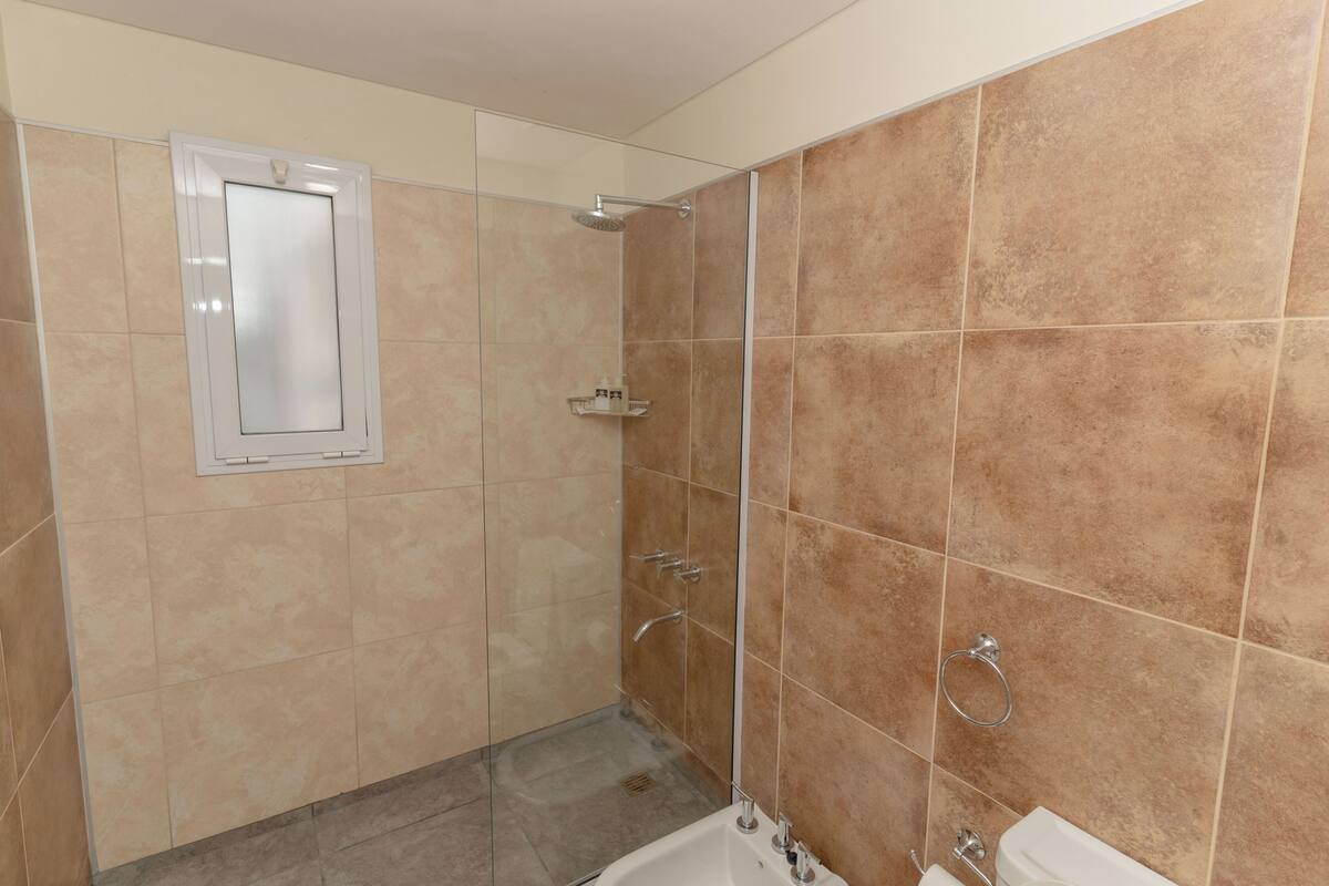 Een badkamer met een douche, toilet en wastafel.