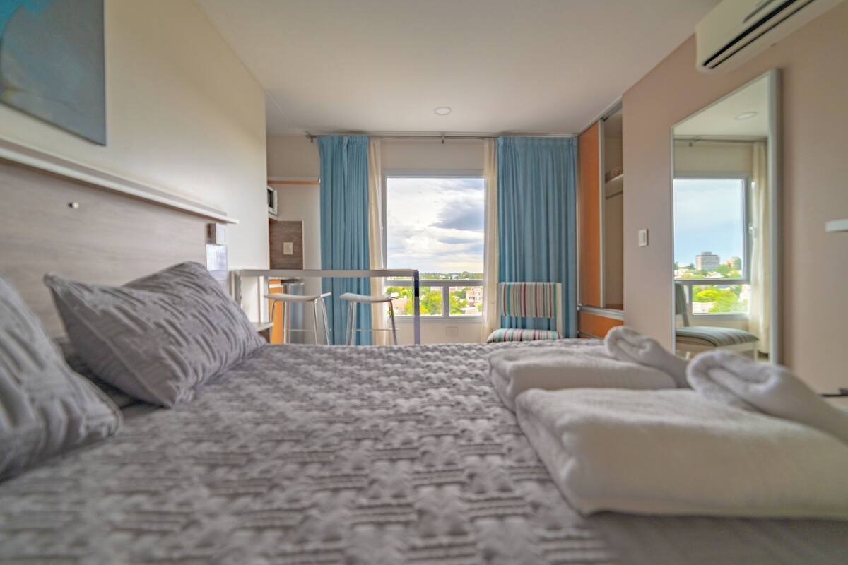 Een hotelkamer met een bed, een balkon met uitzicht en een badkamer.